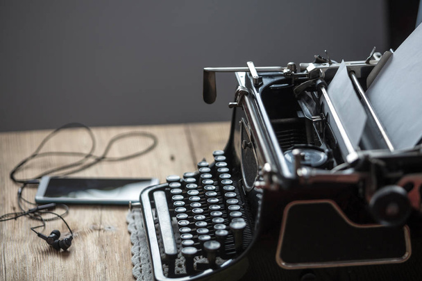 Workplace of an old school writer with mobile phone headphones and a typewriter - 写真・画像