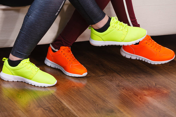 Two unrecognizable women wearing sport shoes, red and neon green ones. Workout outfit pieces. - Fotoğraf, Görsel