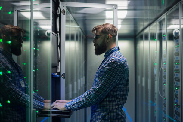 Бородатый ИТ-специалист устанавливает серверы в дата-центре
 - Фото, изображение