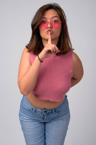 Jeune belle femme asiatique portant des lunettes en forme de coeur avec doigt sur les lèvres
 - Photo, image