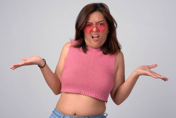 Jeune femme asiatique confus avec des lunettes en forme de coeur haussant les épaules
 - Photo, image