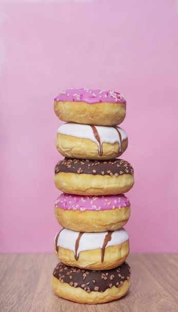 Stack of sweet glazed donuts. Vertical image with pink background. - Foto, immagini