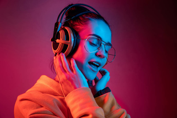 Fashion pretty woman with headphones listening to music over neon background - Foto, immagini