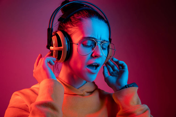 Fashion pretty woman with headphones listening to music over neon background - Fotografie, Obrázek