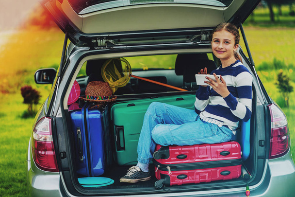 Summer vacation, young girl in the car trunk  is ready for travel for family vacation. - Фото, изображение