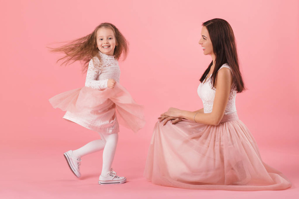 charming mother and smiling daughter on pink background - Photo, image