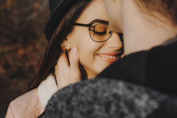 Gros plan d'un beau jeune couple embrassant tandis que le garçon tient le visage de sa petite amie alors qu'elle sourit les yeux fermés à l'extérieur
. - Photo, image