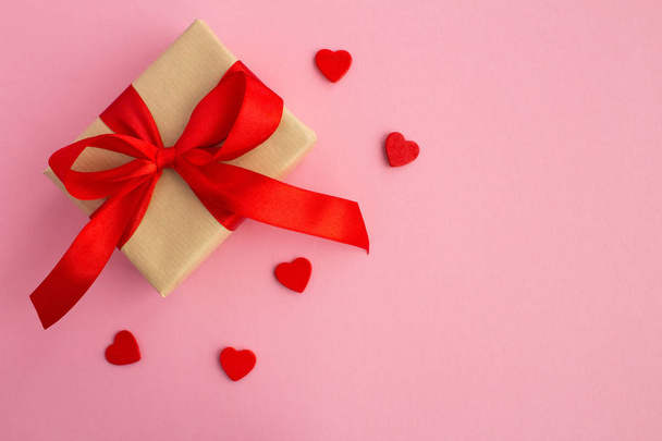 Gift with red bow and small red hearts  on the pink background.Top view.Copy space. - Photo, image