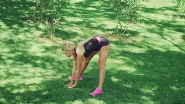 Athlete woman doing stretching slopes down before fitness workout in park - Filmmaterial, Video