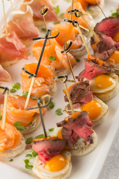 Festive Appetizer with quail egg, salmon and roast beef - Zdjęcie, obraz
