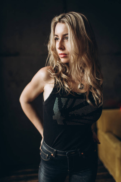Portrait of a beautiful fashionable woman, blonde, jeans, brown background - Valokuva, kuva