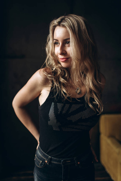 Portrait of a beautiful fashionable woman, blonde, jeans, brown background - Fotó, kép