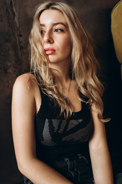 Portrait of a beautiful fashionable woman, blonde, jeans, brown background - Fotografie, Obrázek