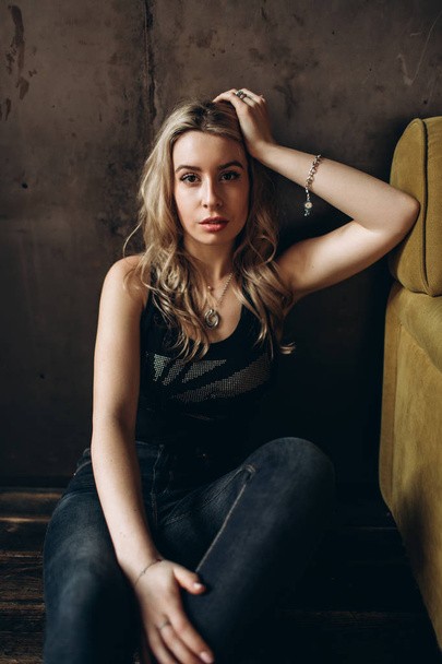 Portrait of a beautiful fashionable woman, blonde, jeans, brown background - 写真・画像