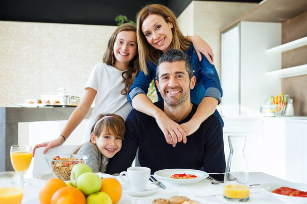 Muotokuva onnellinen kaunis perhe katselee kameraa keittiössä kotona
. - Valokuva, kuva