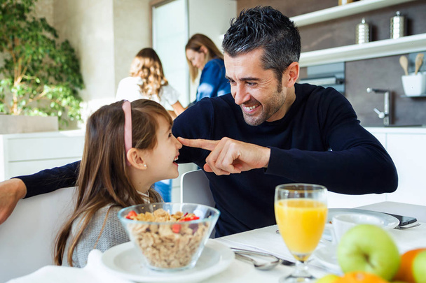 Tiro de sorrindo bonito pai e filha se divertindo enquanto toma café da manhã em família na cozinha em casa
. - Foto, Imagem