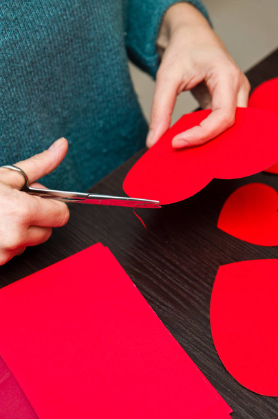Γυναικεία χέρια απασχολημένος με καρδιές χαρτί cut-outs-ημέρα του Αγίου Βαλεντίνου.  - Φωτογραφία, εικόνα