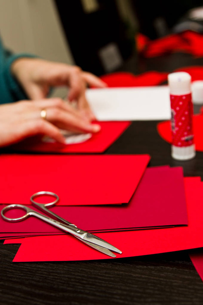 Manos femeninas ocupadas con los recortes de corazones de papel del día de San Valentín
.  - Foto, imagen