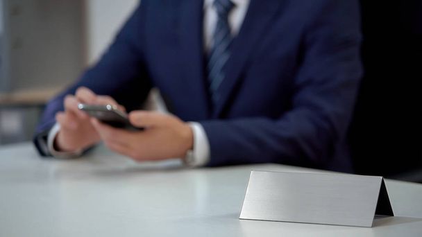 Businessman scrolling on smartphone in office, blank nameplate template for text - Fotoğraf, Görsel