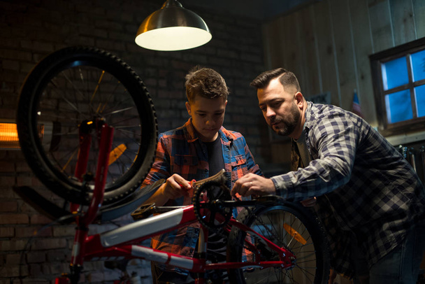 Vater und Sohn reparieren ein Fahrrad in einer Garage - Foto, Bild