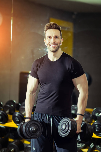 Сила концепции Здоровый образ жизни Спорт Мощный мускулистый человек тренируется в тренажерном зале делая упражнения на бицепсах с гантелями
 - Фото, изображение