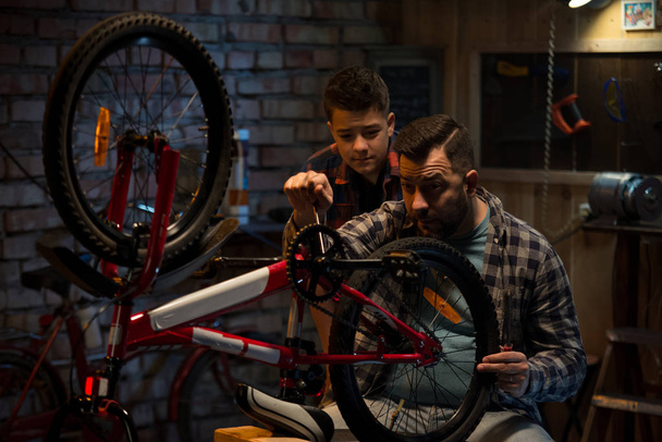 Батько і син говорять про ремонт велосипедів
 - Фото, зображення