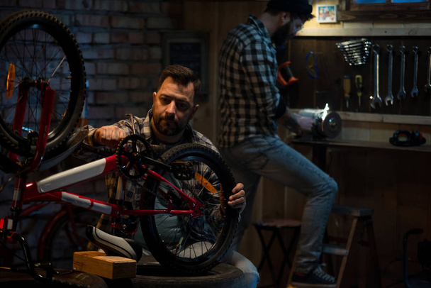 Twee mannen aan het werk in een fietswinkel voor reparatie - Foto, afbeelding