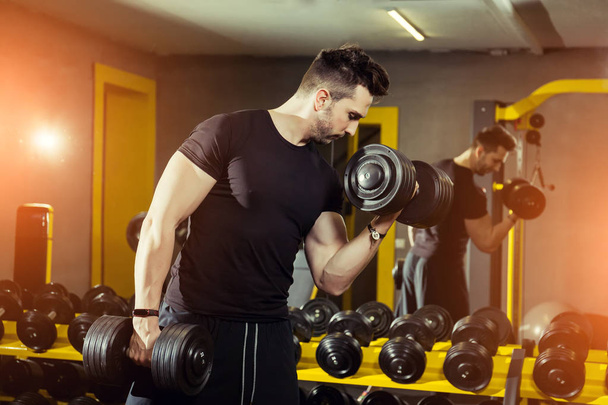 Conceito Força de energia Estilo de vida saudável Esporte Poderoso Muscular homem trabalhando no ginásio fazendo exercícios no bíceps com halteres
 - Foto, Imagem