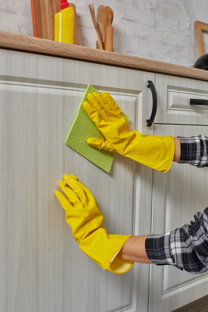 Руки в перчатках с зеленой тряпкой уборка кухни шкафы - домашнее хозяйство и домашнее хозяйство концепции
 - Фото, изображение