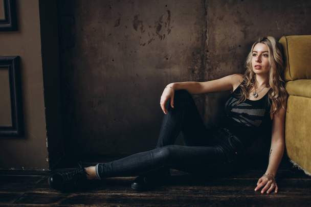 Portrait of a beautiful fashionable woman, blonde, jeans, brown background - 写真・画像