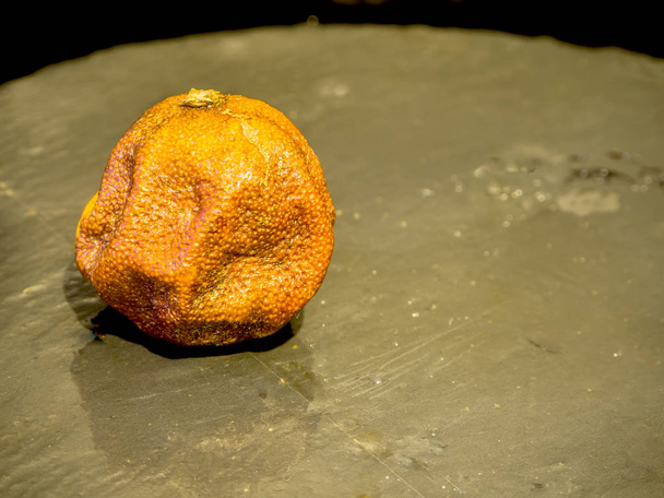 Rotten mandarin ob black stone - Photo, Image