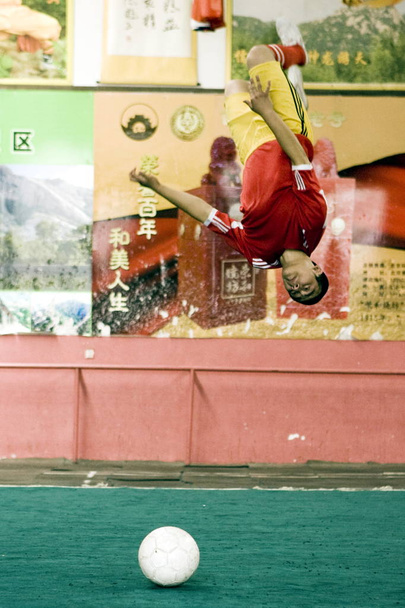 Un futbolista chino de kungfu salta volando sobre un fútbol durante una sesión de entrenamiento en el Shuaimingke Kungfu Football Club en Beijing, China, 5 de junio de 2010
 - Foto, imagen