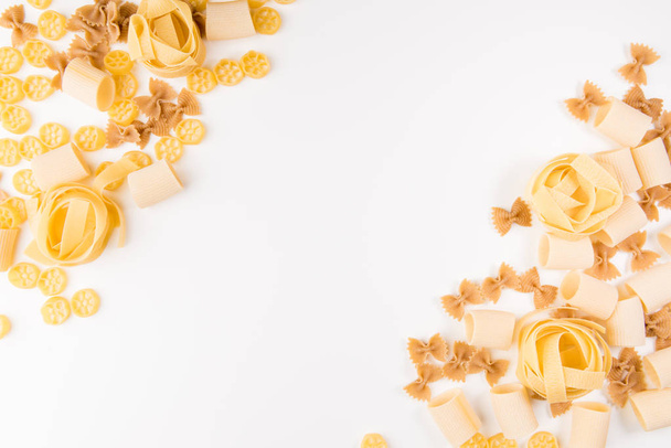 Una foto de arriba de diferentes tipos de pasta, incluyendo espaguetis, penne, fusilli y otros, flay lay on a white background with a place for text
 - Foto, imagen