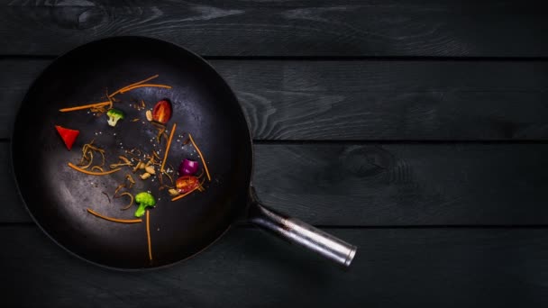 Animação. Ingredientes para macarrão wok em uma frigideira para fritar em um fundo de madeira preta
 - Filmagem, Vídeo