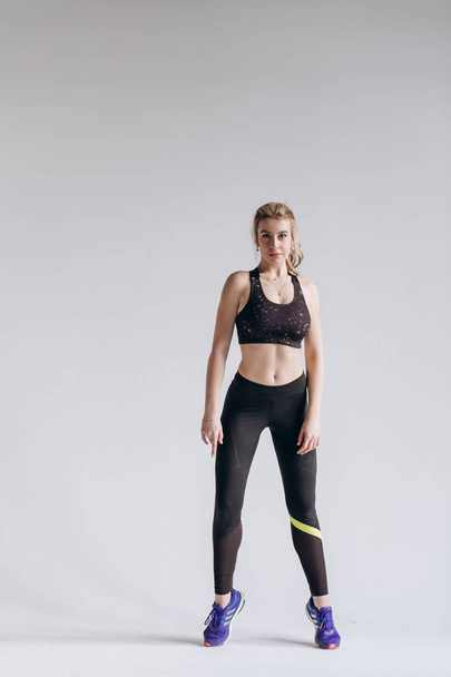 Ganzkörperporträt einer jungen Fitness-Frau in Sportbekleidung, die isoliert über grauen Hintergrund posiert und springt - Foto, Bild