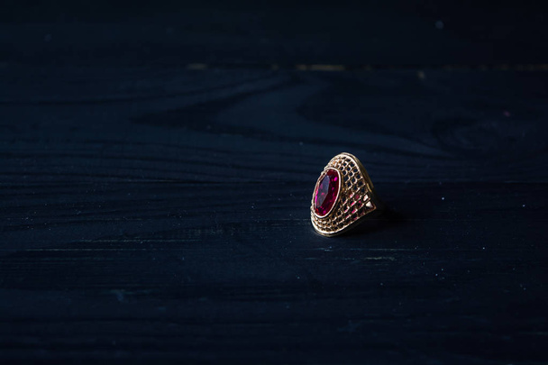 Золоте кільце з червоним каменем ізольовано на чорному тлі
 - Фото, зображення