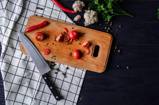 Вишневі помідори на дерев'яній дошці з часником, перцем та спеціями на кухонному рушнику
 - Фото, зображення