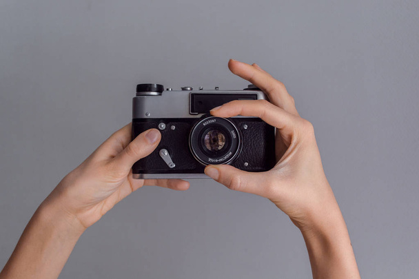 Руки женщины держат ретро-фотокамеру на сером фоне стены
 - Фото, изображение