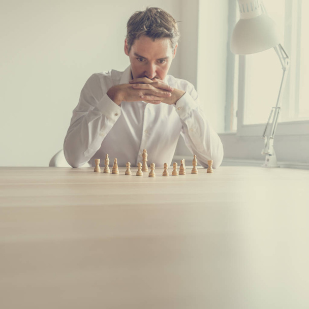 Business-Arbeitgeber Brainstorming, um den besten strategischen Schachzug in einem konzeptionellen Bild zu machen, wie er Schachfiguren auf dem Bürotisch positioniert hat. - Foto, Bild