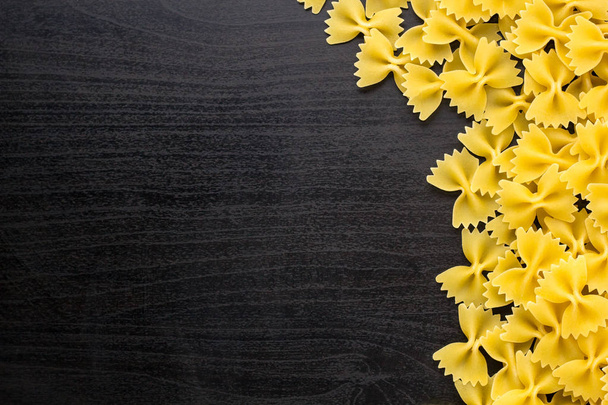 Кордон з купою макаронних виробів Farfalle на темно-чорному тлі з копійкою
 - Фото, зображення