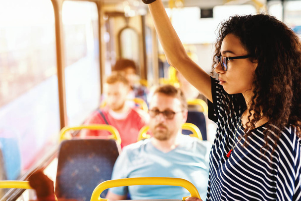 young cheerful woman in headphones standing in bus  - Valokuva, kuva