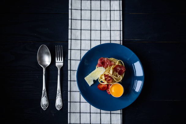 Macarrão carbonara em uma mesa com produtos frescos no fundo escuro, espaço de cópia, fundo de comida
   - Foto, Imagem