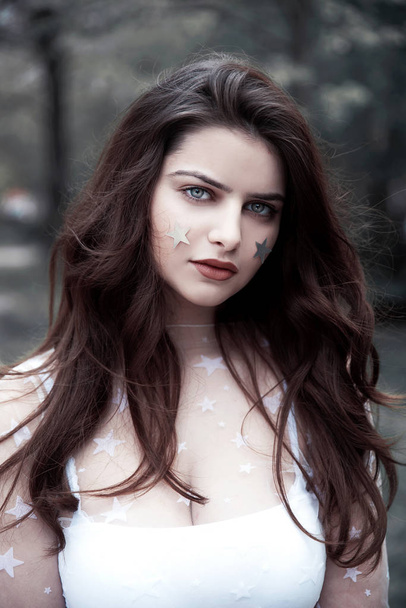 Young brunette woman with stars on her face standing outdoors - Foto, Imagem