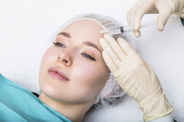 Woman receiving skin beauty injection in forehead - Zdjęcie, obraz