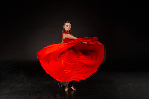 Красива молода дівчина танцює. Дівчина з літаючою червоною сукнею
. - Фото, зображення