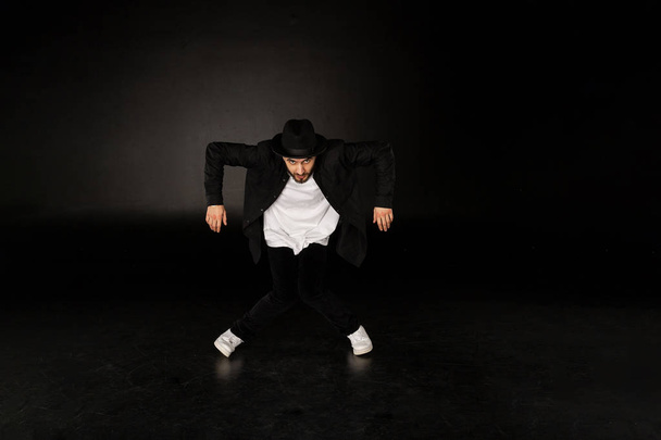 Knappe man, gekleed in een stijlvolle zwarte kleding danst Streetdance - Foto, afbeelding