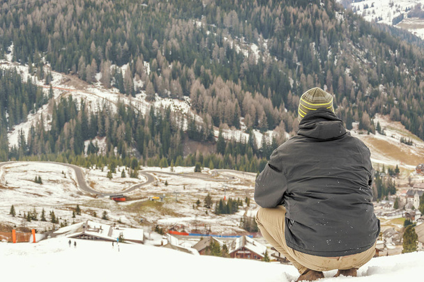 Молода людина сидить на снігу і дивляться поблизу курорті Корвара, Долина регіоні Альта-Бадія - Фото, зображення