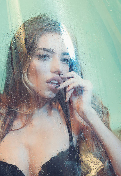 Sexy woman in shower. Attractive young naked woman under water drops on blue background - Fotó, kép