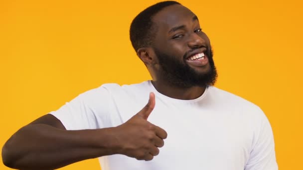 Cheerful African-American man showing thumbs up isolated on yellow background - Záběry, video