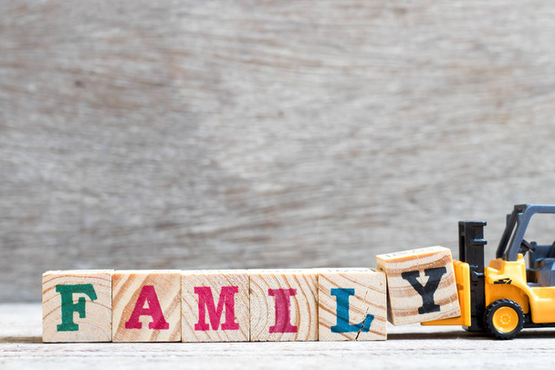 Spielzeug Gabelstapler halten Buchstabenblock y, um Wortfamilie auf Holz-Hintergrund zu vervollständigen - Foto, Bild